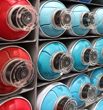 Close-up of red and blue spray paint cans on shelves