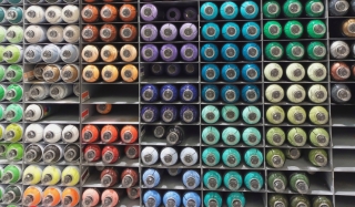 Wall of colourful aerosol spray paint cans on shelves