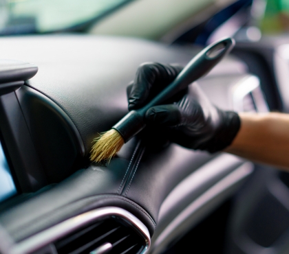 Gloved hand brushing a car dashboard clean